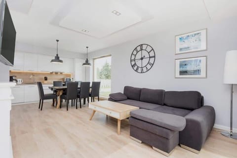 A dining area in a modern open-plan living space, with a black table and chairs, large windows, and minimalist decor, giving it a sophisticated yet welcoming feel.