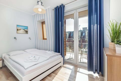 Bright and cosy bedroom with blue curtains and comfortable bed for two people.