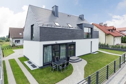 The exterior of a modern house with a sleek, minimalist design features clean white walls, large windows, and a well-kept lawn, creating a contemporary and stylish look.