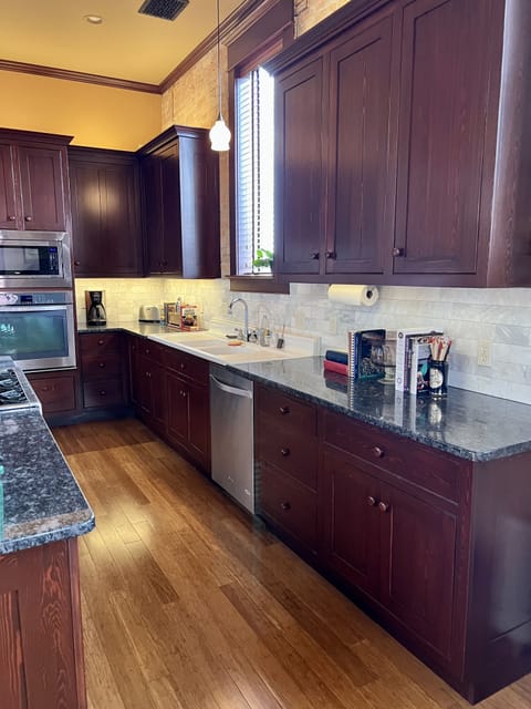 Open concept kitchen with gas Wolf stove, antique sink and granite countertops.