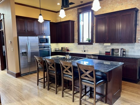 Open concept kitchen with gas Wolf stove, antique sink and granite countertops.