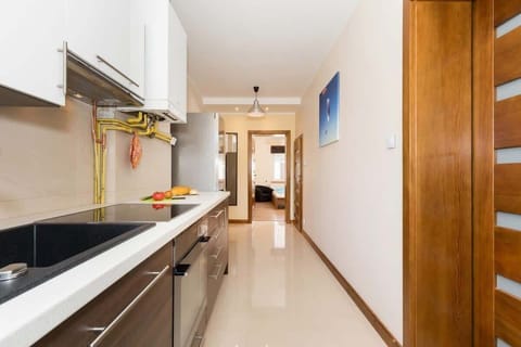 A view of the kitchen from a different angle. Brown and white cabinets. Carny sink and hob.