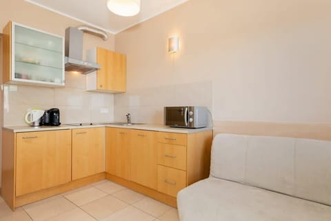 A compact kitchen with light wood cabinets, white countertops, and basic appliances. Simple and practical design.