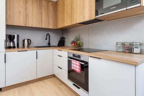 A stylish kitchen corner with minimalist wooden cabinets, modern appliances, and a clean, white countertop.