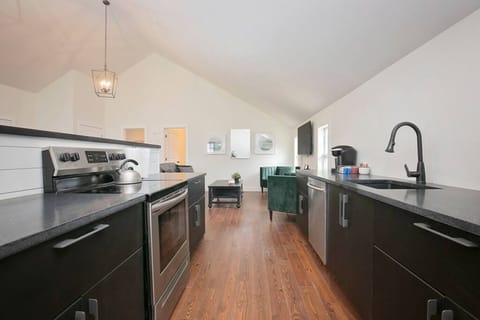 Modern kitchen with sleek black cabinets, stainless steel appliances, and an open layout.