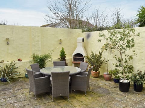Enclosed paved patio with outdoor furniture and a built-in BBQ | The Old Butchers, Crantock, near Newquay
