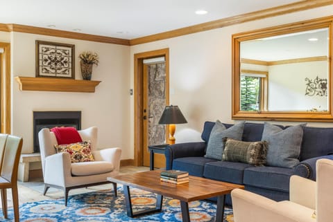Living room with navy sofa, wingback chair, wooden coffee table, patterned rug, and a gas fireplace.