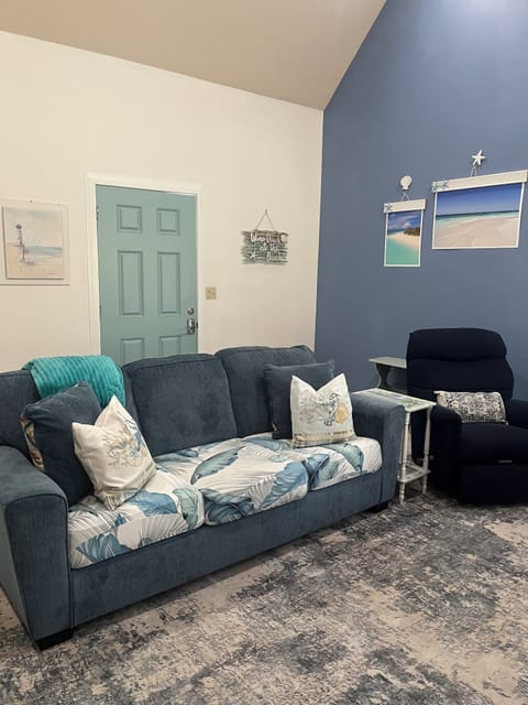 Living room with queen sleeper sofa, large TV, recliner and small dining table.