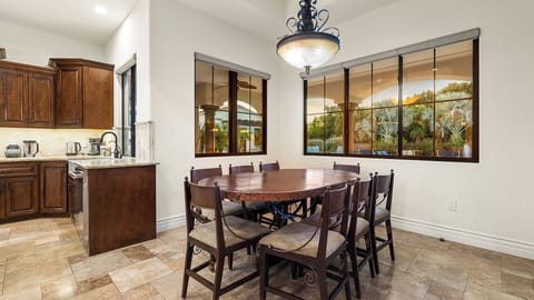 Cozy dining with rustic table, elegant lighting & lush backyard views!