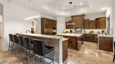 Spacious gourmet kitchen with wood cabinetry, modern lighting & large island!