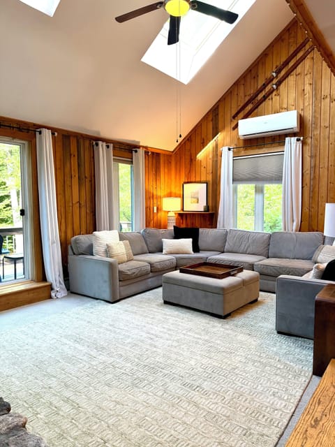 Living room with big sectional couch, tv, and air conditioner. 