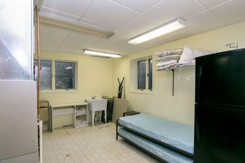 View of laundry room with ironing board, backup cots, second fridge.