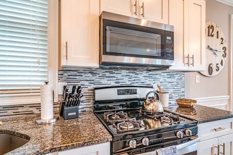 Modern kitchen with stainless steel gas range and granite counters