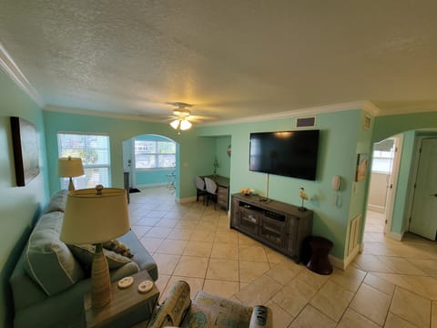 Main living room area with queen sofa bed, desk/work station, TV and wet bar.