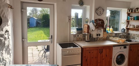 Bright kitchen leading to patio and fenced garden 