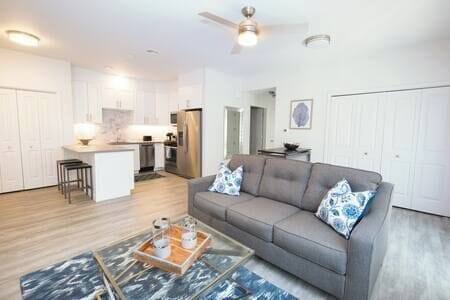 Cozy living area with couch, smart TV, full kitchen, bar seating, dining table, and patio access (2)