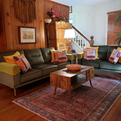 Spacious retro-themed living room, with velvety sofa and loveseat. 