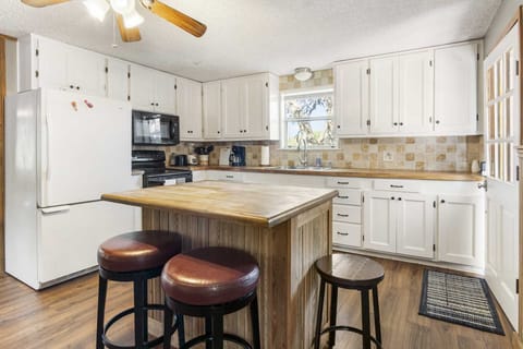 Spacious farmhouse kitchen with white cabinets, rustic island, and scenic window views-perfect for family meals and morning coffee