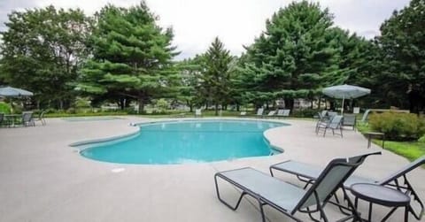 Outside pool hosts lawn chairs, tables and umbrellas.