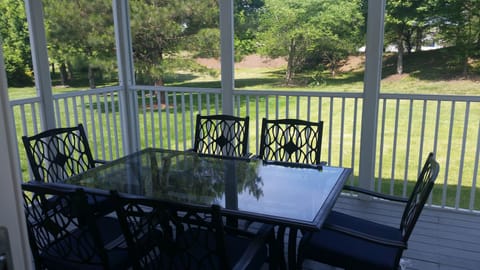 Outdoor dining in the screened porch overlooks a large backyard.