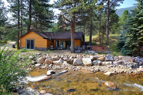 View of side of cabin from across river. Patio, hot tub, fire pit, gas grill.
