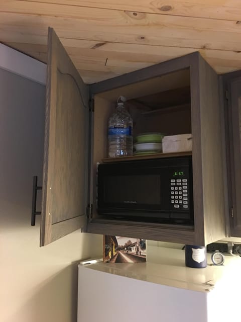 Microwave built into cabinet above fridge