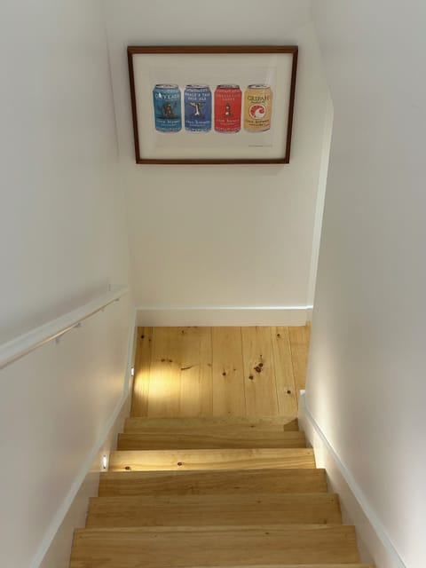 Well lit stairs to basement with Cisco Brewery art work