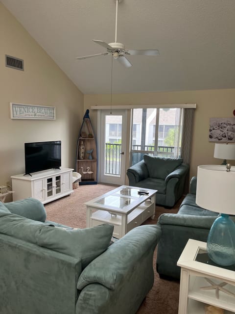 Living room with pull out couch, love seat, chair, TV, and a view of the lake. 