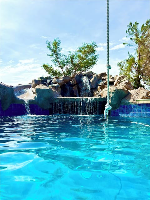 MASSIVE amazing pool with rope swing, rock water feature and slide.