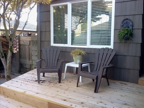 Rear deck overlooks large, fenced courtyard with table and chairs.