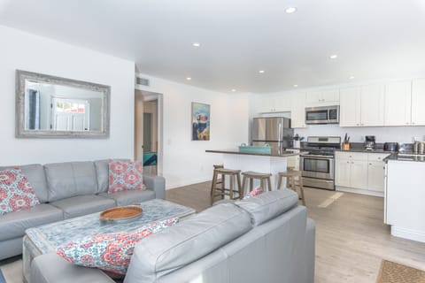Front door opens up to the main living area, with a sofa set, cable TV, and open kitchen area.