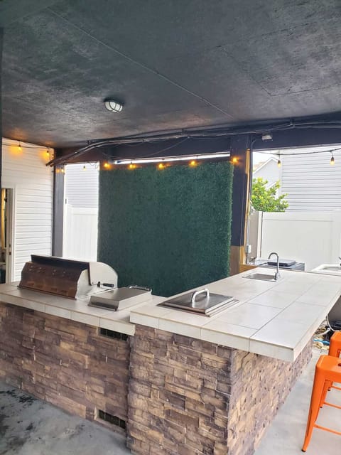 This space features a sleek grill, perfect for sizzling burgers and steaks, set against a lively backdrop of a fun grass wall. The ambiance is enhanced by lush greenery and soft lighting, creating an inviting atmosphere for summer gatherings. Whether you're hosting a casual barbecue or a sophisticated dinner party, this outdoor grill oasis promises to delight both the palate and the senses.