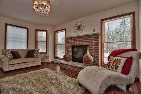 Relaxing room, red brick gas fireplace, couches, lounge chair, lots of light