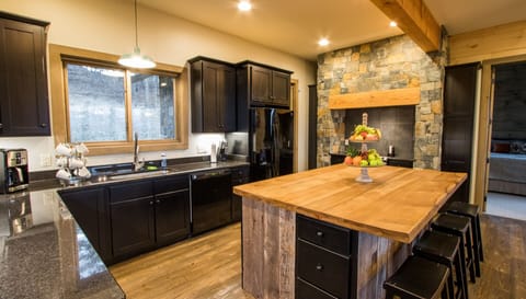 Stone hearth around modern range creates stunning feature in huge open kitchen
