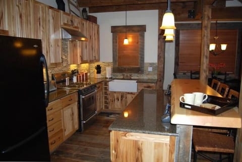 Custom kitchen with granite counters, farmhouse sink, and hand made log bar.