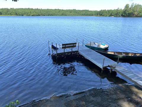 Beach area and dock complete with dock bench, canoe, and paddle boat. 
