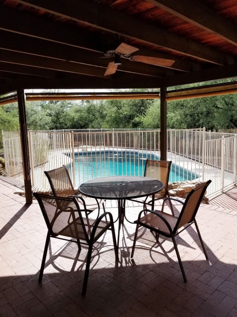 Table and chairs overlooking pool with roll down sun shades and outdoor fan