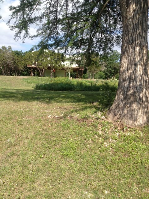Photo standing on river bank, facing the front of the house.