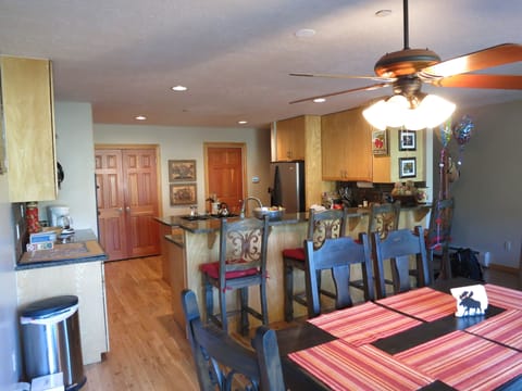 Kitchen and dining table ith 4 bar stools.  Additional seaaing outside.