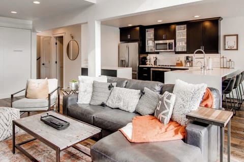 Updated kitchen with quartz waterfall counters and bar seating, and leather sectional sofa.