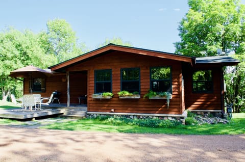 View of the front of the lodge and deck with patio set and charcoal bbq