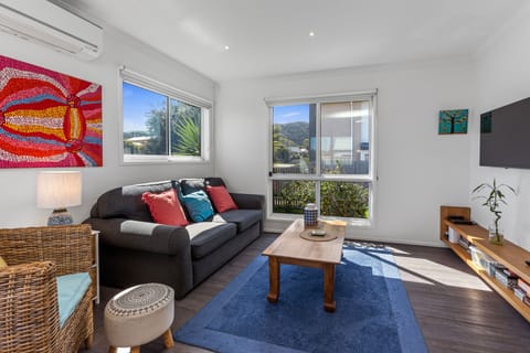 Comfortable lounge area with large smart TV and blinds on windows.