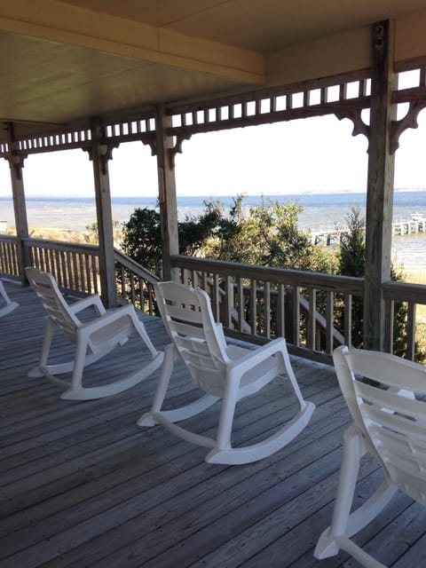Wraparound porch rocking chairs, captains chairs, picnic table overlooking sea.