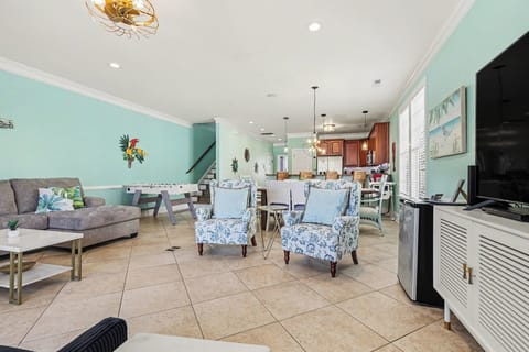 Spacious open-concept living area featuring stylish coastal furnishings, foosball table for fun nights in, and seamless flow to the kitchen and dining space.