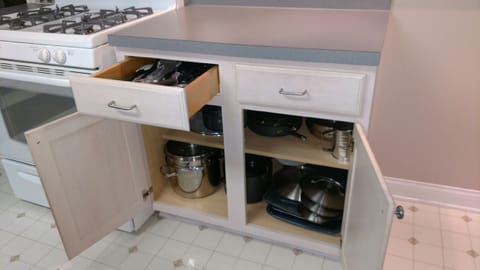 Kitchen-cooking utensils in drawer, pots and pans below.