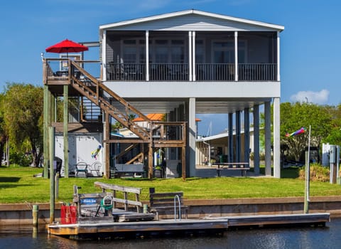 Back view from across the canal, showing dock, deck, elevator and screened porch