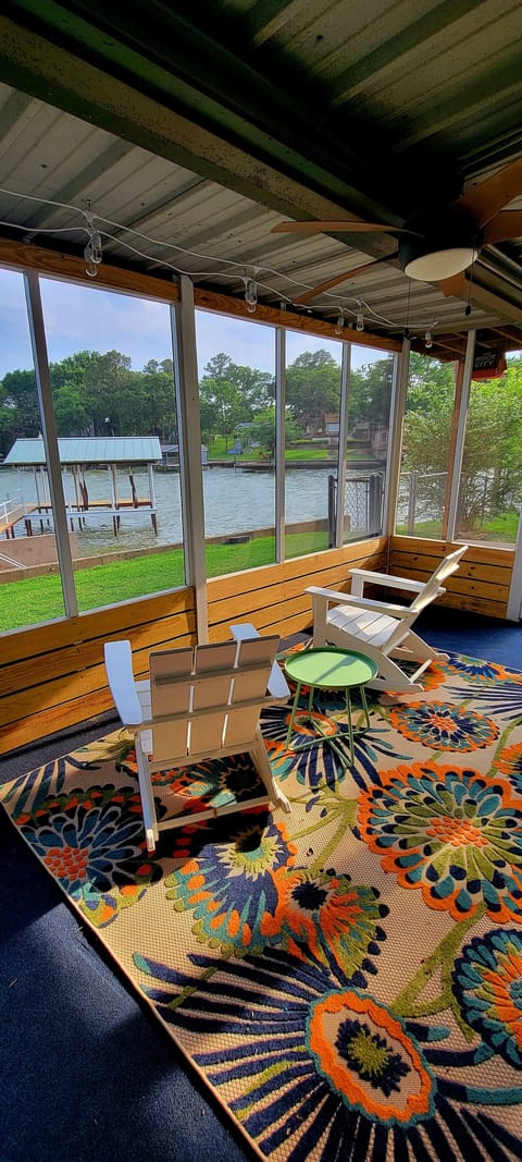 Waterfront rocking chairs on screen porch with string lights for nighttime.