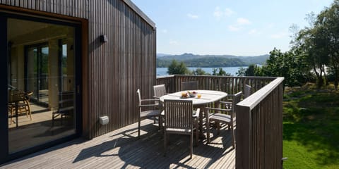 The raised deck has a teak dining table and chairs 