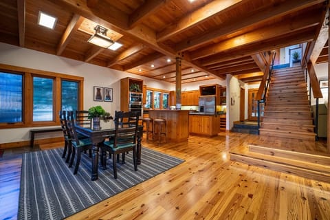 Dining table with open kitchen design and central staircase.
