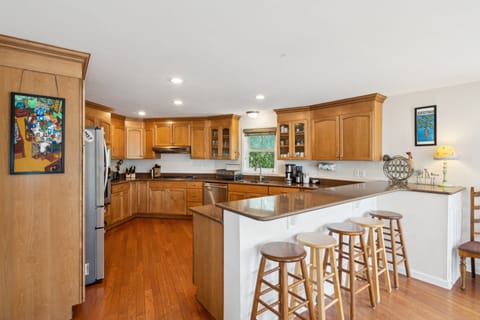 Large kitchen with bar seating for four and stainless steel appliances.